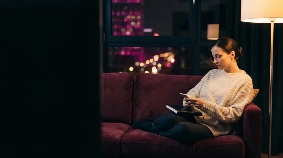 Kobieta w półmroku planuje start z telefonem i notesem